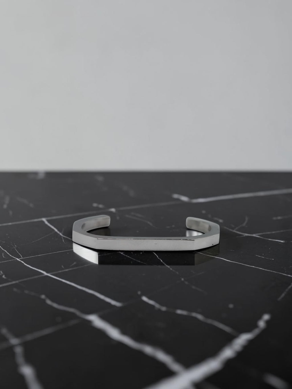 Silver open cuff bracelet on a black marble surface
