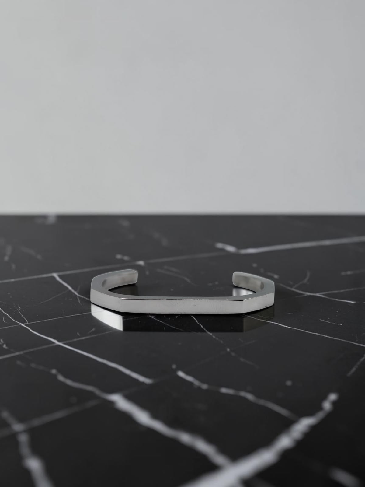 Silver open cuff bracelet on a black marble surface